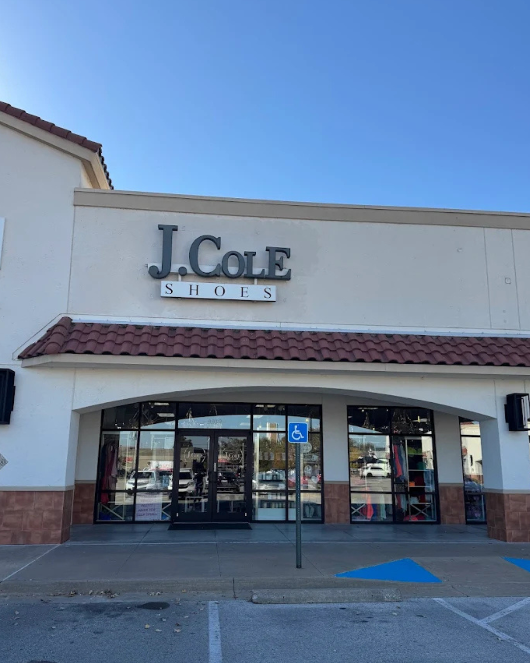 Exterior storefront of J. Cole Shoes boutique with a tiled roof and large glass windows.