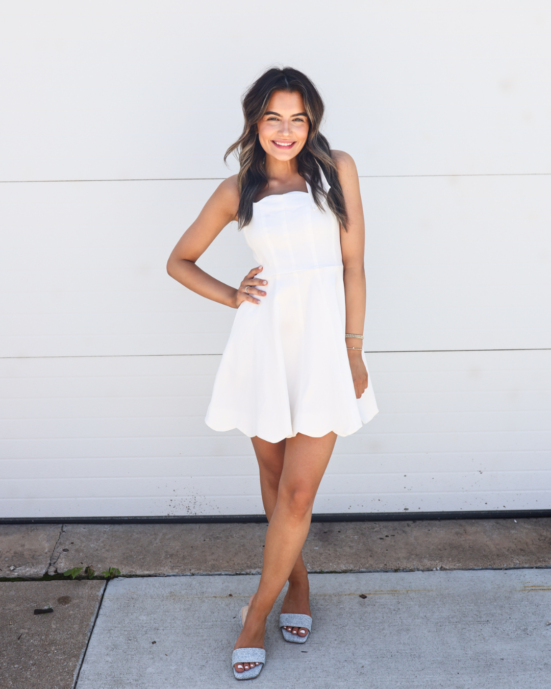 Woman wearing a short white flared dress and grey heeled sandals for OSU Rush Week.