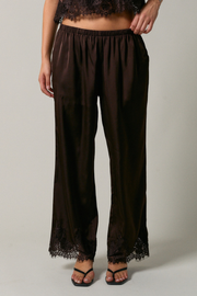 Brown lace-trimmed pants worn by a person on a plain background