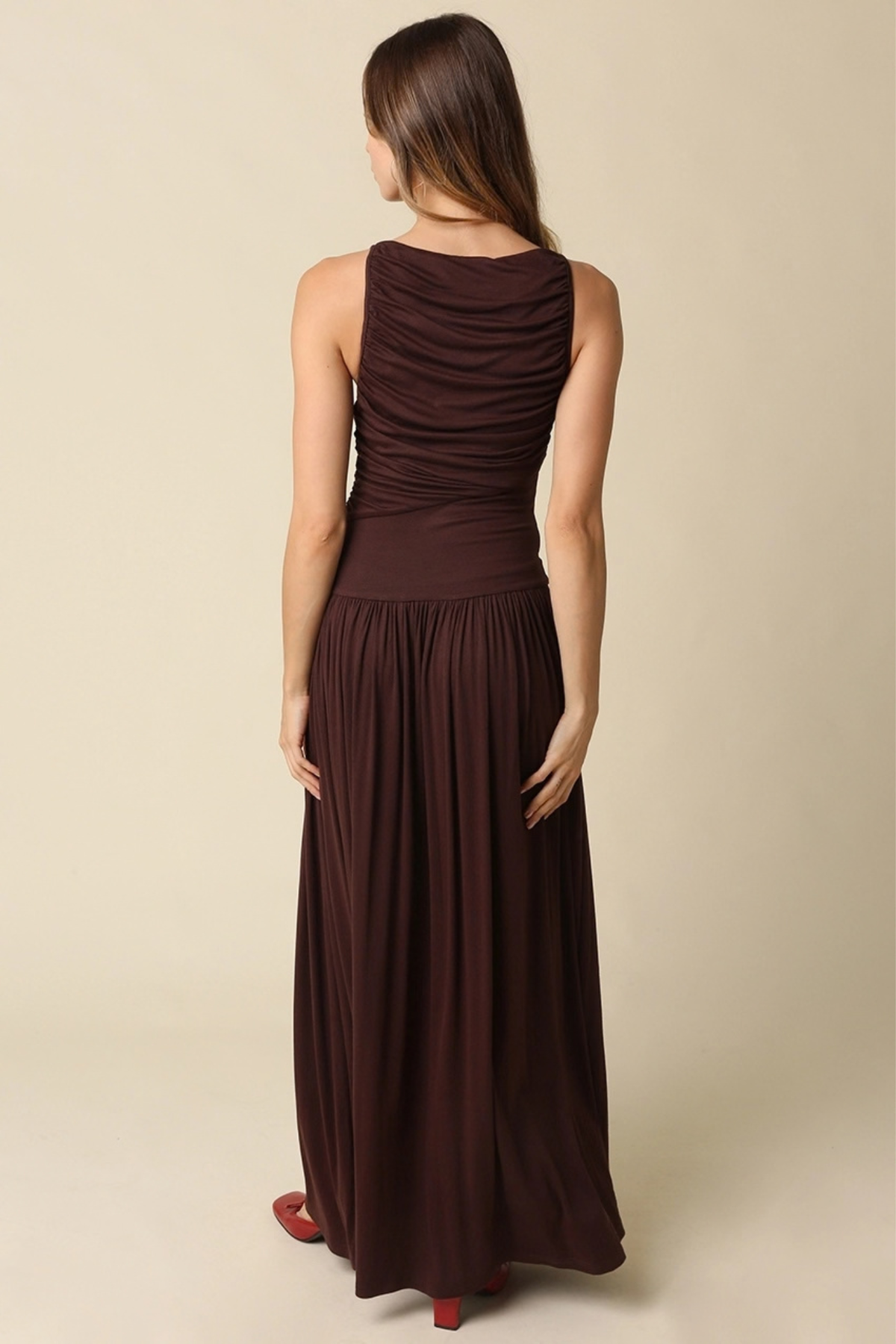 Woman wearing a brown sleeveless dress against a beige background