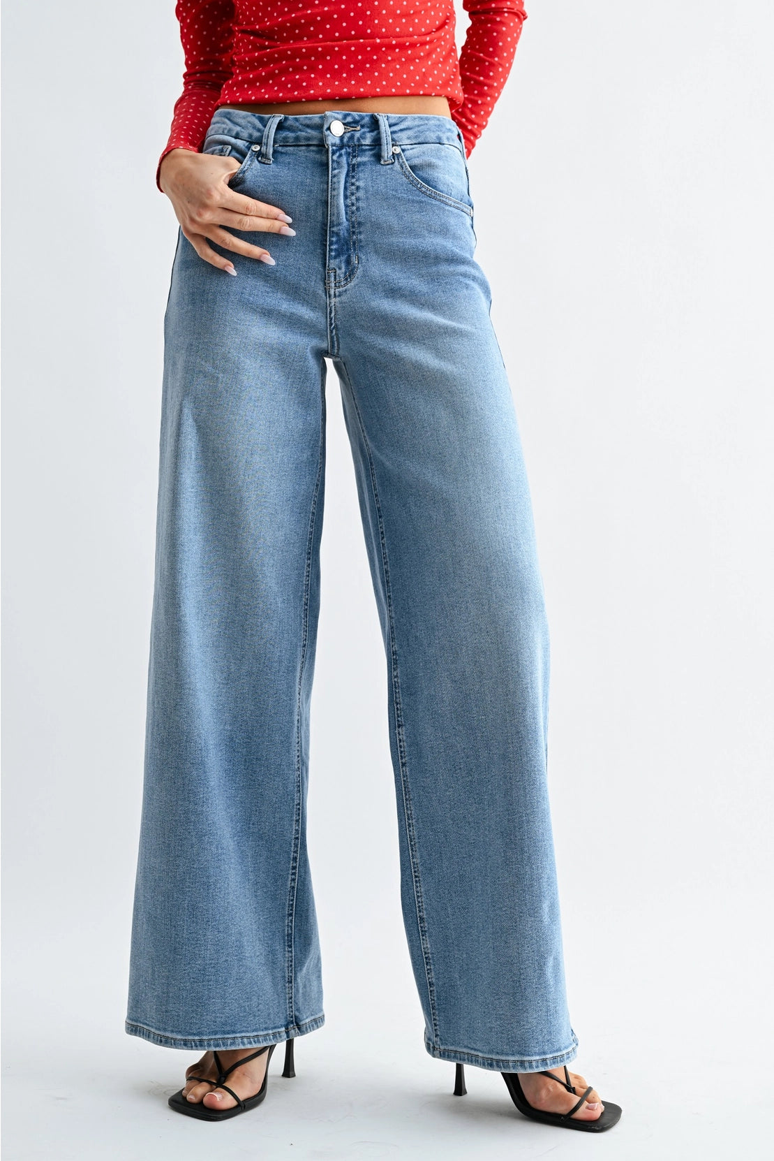 Person wearing blue wide-leg jeans and a red top on a light gray background