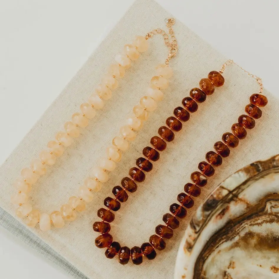 Two beaded necklaces on a textured surface with a neutral background