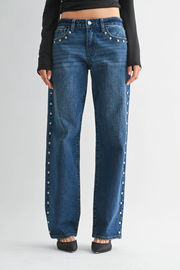 Blue jeans with decorative studs on a plain background