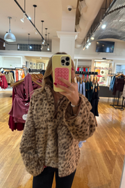 A woman takes a mirror selfie at J.Cole Shoes in Stillwater wearing a fuzzy leopard-print jacket. The jacket has a warm tan base with black leopard spots.