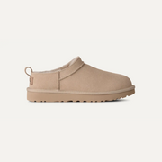 A single UGG slip-on clog shoe in a light tan suede-like material with a matching sole and a small heel pull tab, shown in profile against a plain off-white background.