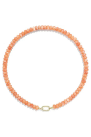 A beaded necklace made of small peach-orange faceted beads with a gold oval link clasp, shown on a plain white background.