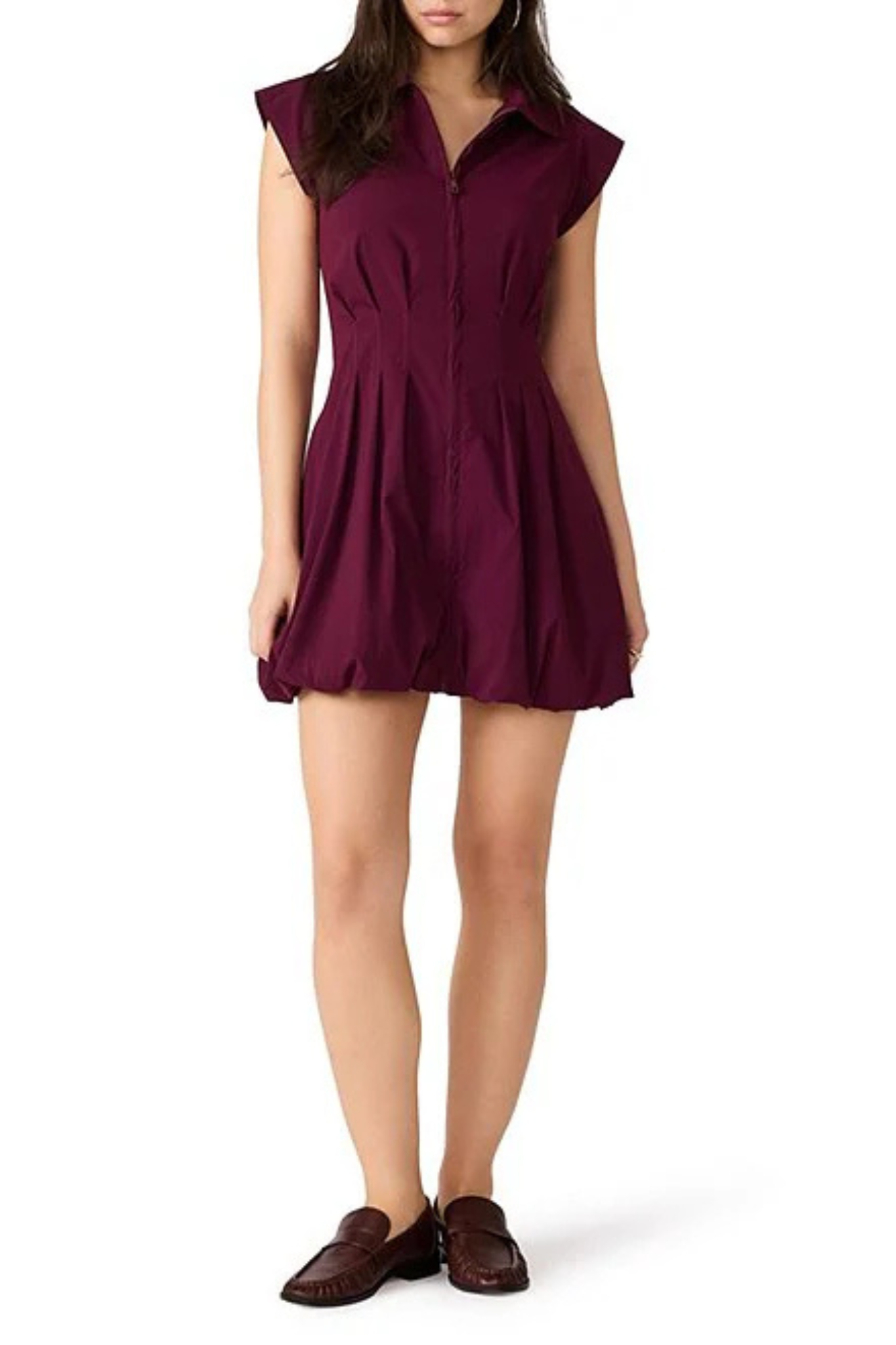 A woman modeling a sleeveless, button-front mini dress in deep burgundy with a flared skirt, paired with dark brown loafers, against a plain white background.