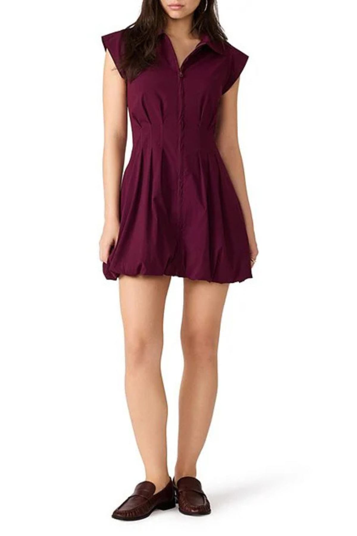 A woman modeling a sleeveless, button-front mini dress in deep burgundy with a flared skirt, paired with dark brown loafers, against a plain white background.