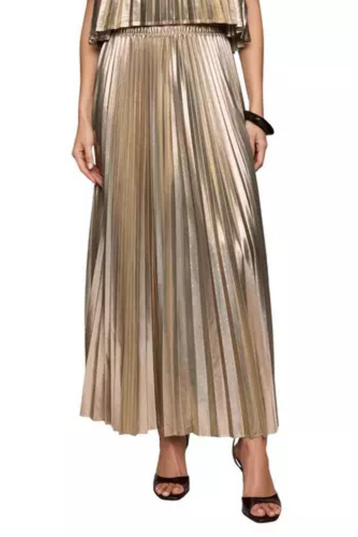 A metallic gold pleated maxi skirt worn by a model, paired with black heeled sandals, shown against a plain white background.