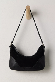 Black handbag with a strap on a light gray background