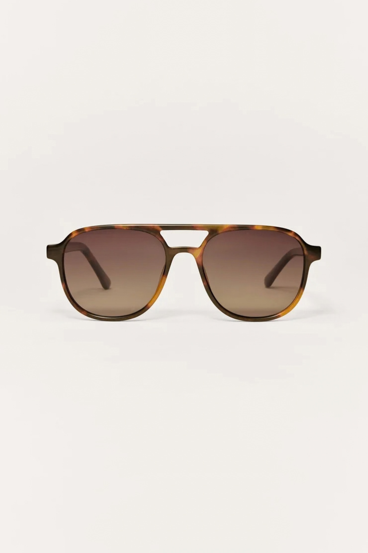 A pair of aviator-style sunglasses with a translucent tortoiseshell frame and gradient brown lenses, shown against a plain off-white background.