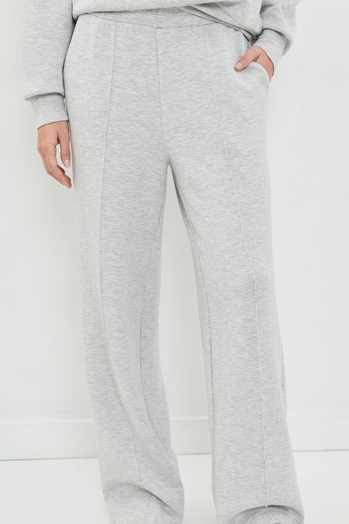 Light heather gray wide-leg sweatpants shown on a model, featuring a relaxed straight fit, side pockets, and a drawstring waist.