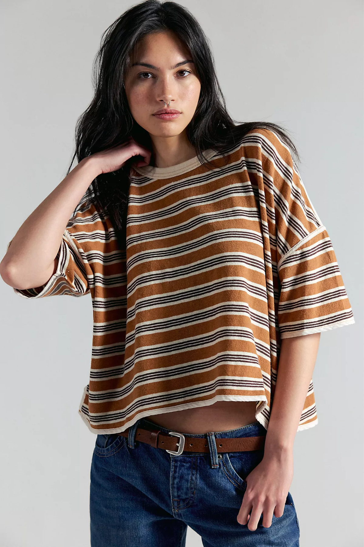 Woman wearing a striped shirt and jeans against a plain background