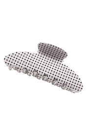 A white hair claw clip decorated with a black polka dot pattern, shown against a plain white background.