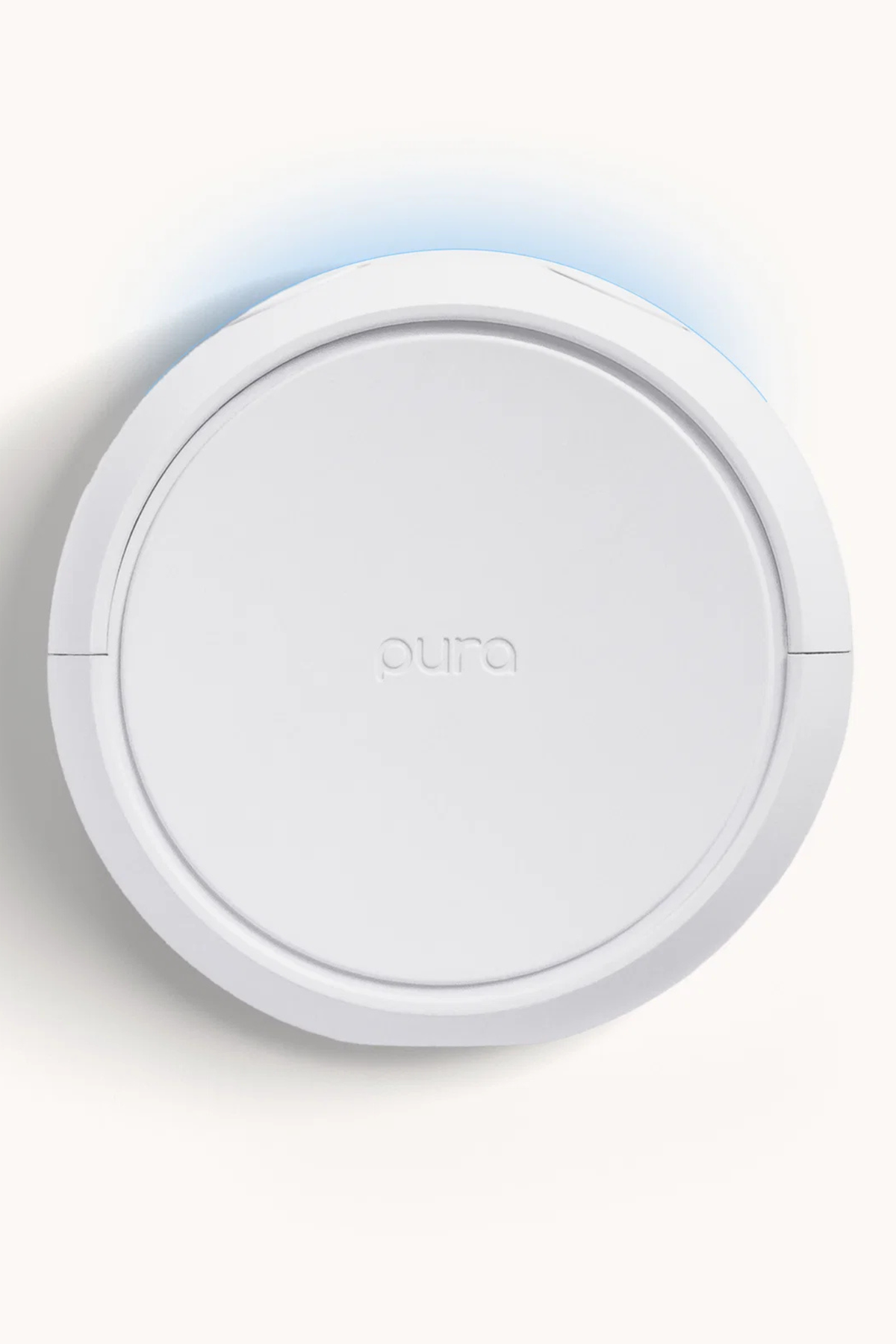 A white round smart home device with the brand name 'pura' embossed in the center, shown against a clean off-white background with a subtle blue light glow above it.