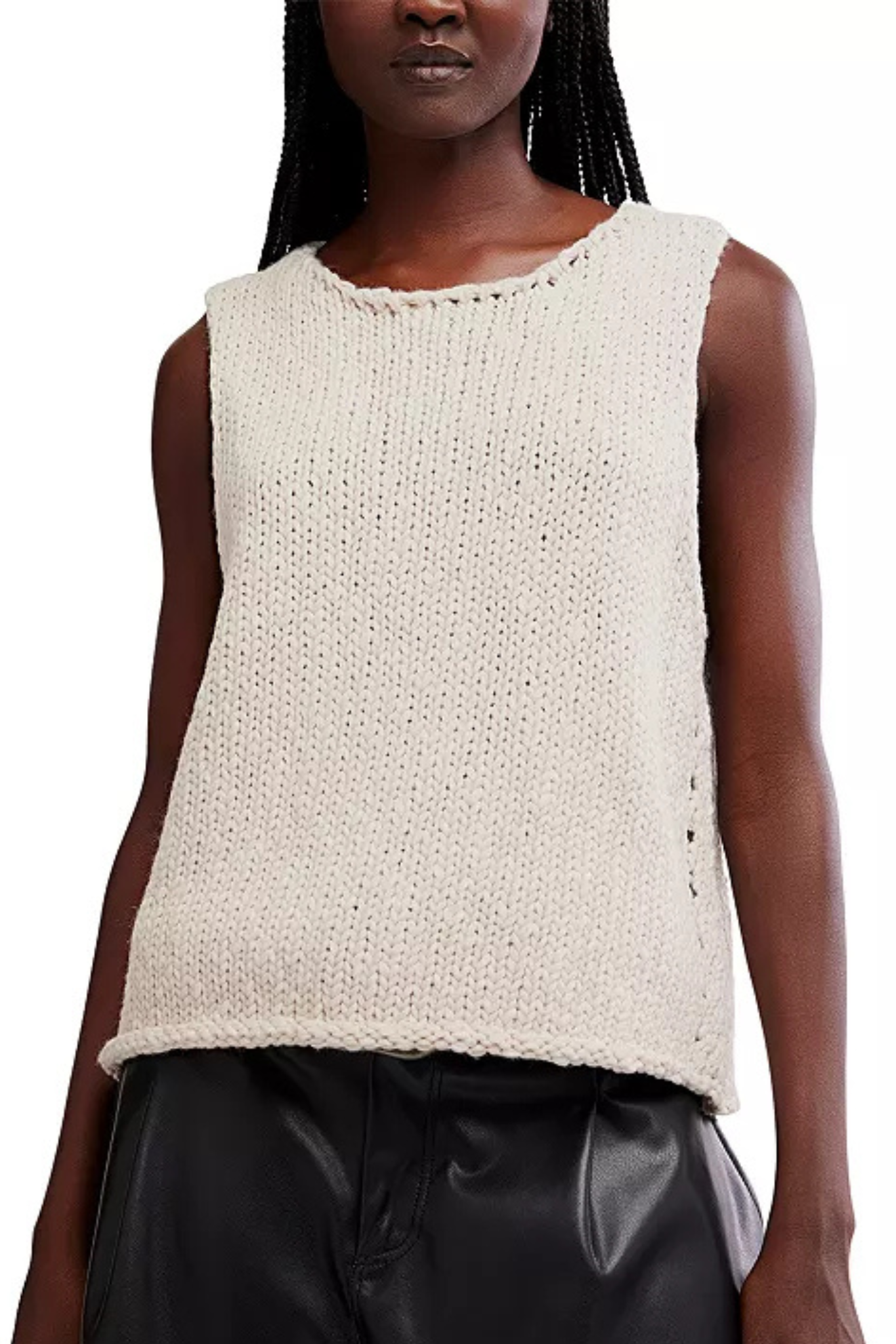 A sleeveless knit top in a warm off-white or cream color, featuring a textured open-knit pattern and a scalloped trim along the neckline, worn by a model with black leather pants against a white background.