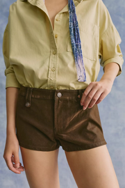 Person wearing a light green shirt and brown shorts against a gray background