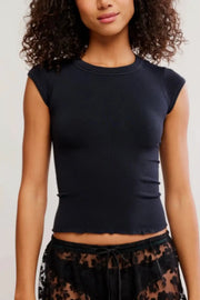 A woman wearing a fitted black short-sleeve crop top with a crew neckline, paired with black lace-patterned bottoms, against a plain light background.