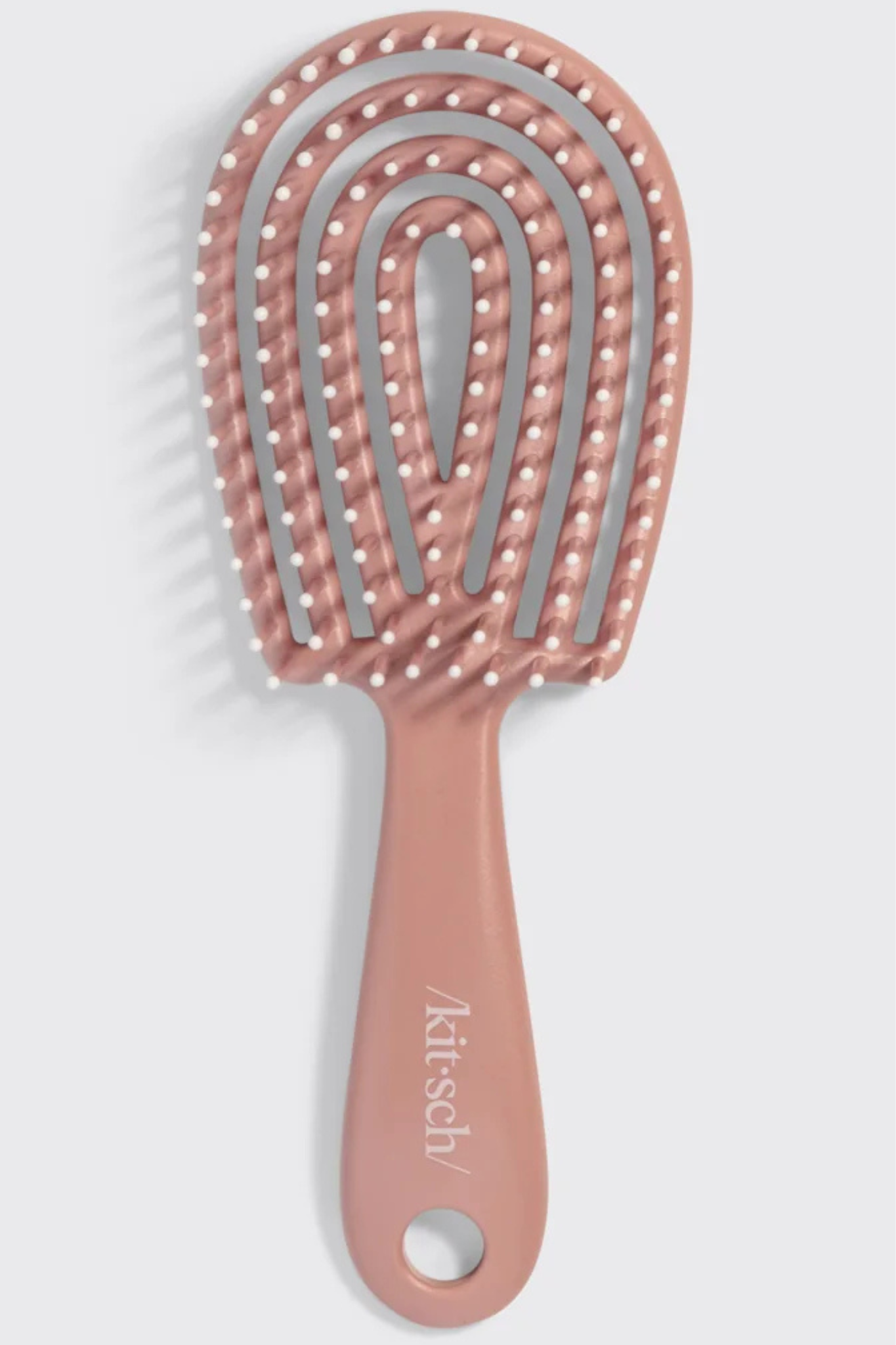A rose gold silicone hairbrush with silver metal wire loops and white silicone bristles, featuring the 'kitesh' brand name printed on the handle, set against a light gray background.