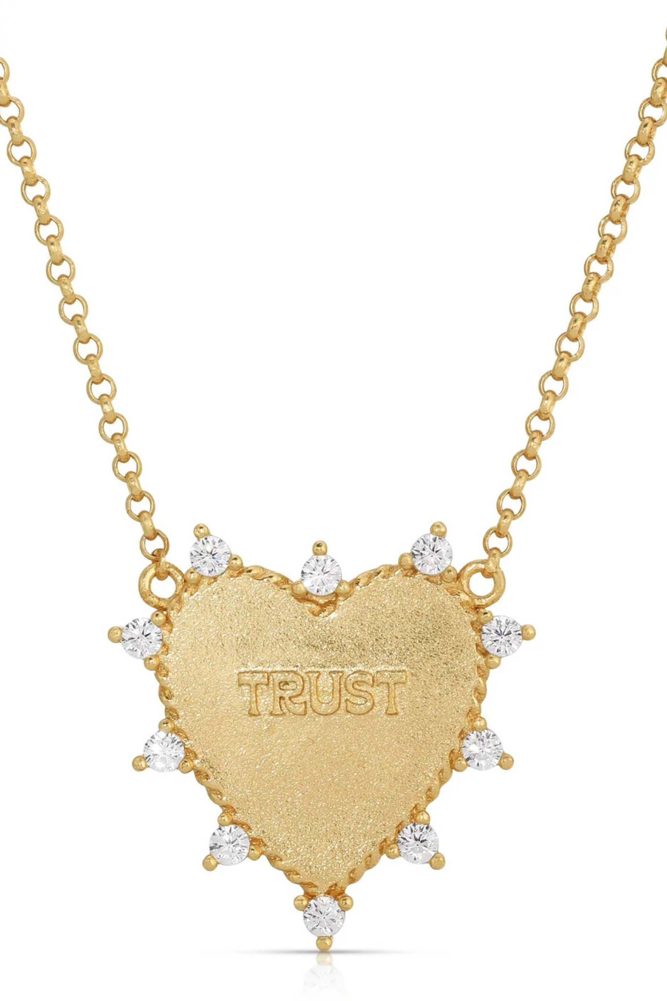 A gold heart-shaped pendant necklace with the word 'TRUST' engraved in the center, surrounded by small clear gemstones along the edge, on a white background.