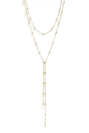 A delicate gold Y-necklace featuring three layered chains with small bead details and a long dangling fringe, shown on a plain white background.