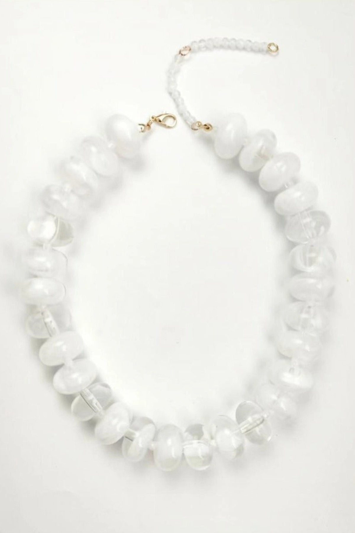 A white beaded necklace made of large, irregular disc-like beads with a gold clasp and extender chain, displayed on a clean white background.