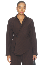 A model wearing a dark brown and black checkered wrap shirt jacket with matching trousers, photographed against a solid white background.