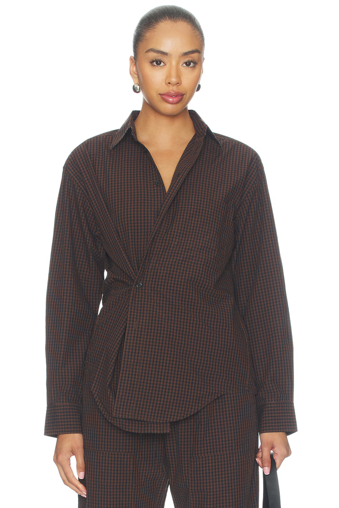 A model wearing a dark brown and black checkered wrap shirt jacket with matching trousers, photographed against a solid white background.