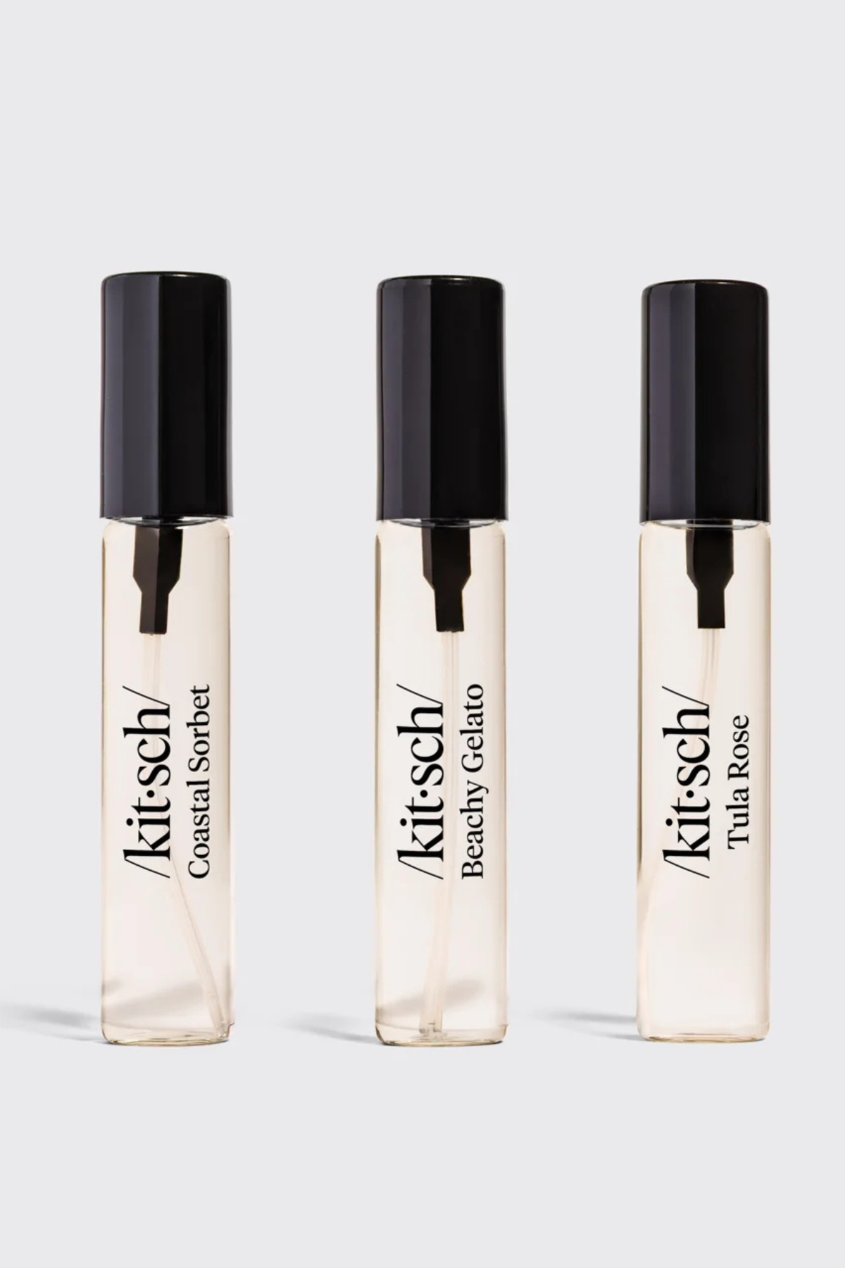 Three Kit:Sch fragrance rollerball bottles in Coastal Sorbet, Beachy Gelato, and Tula Rose scents, arranged side-by-side on a light gray background.
