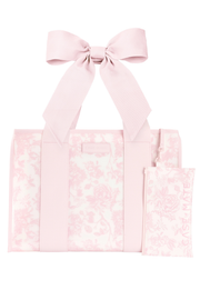 A light pink tote bag with a matching fabric bow on the handle and a small matching pouch, both featuring a subtle floral damask pattern, shown on a plain white background.