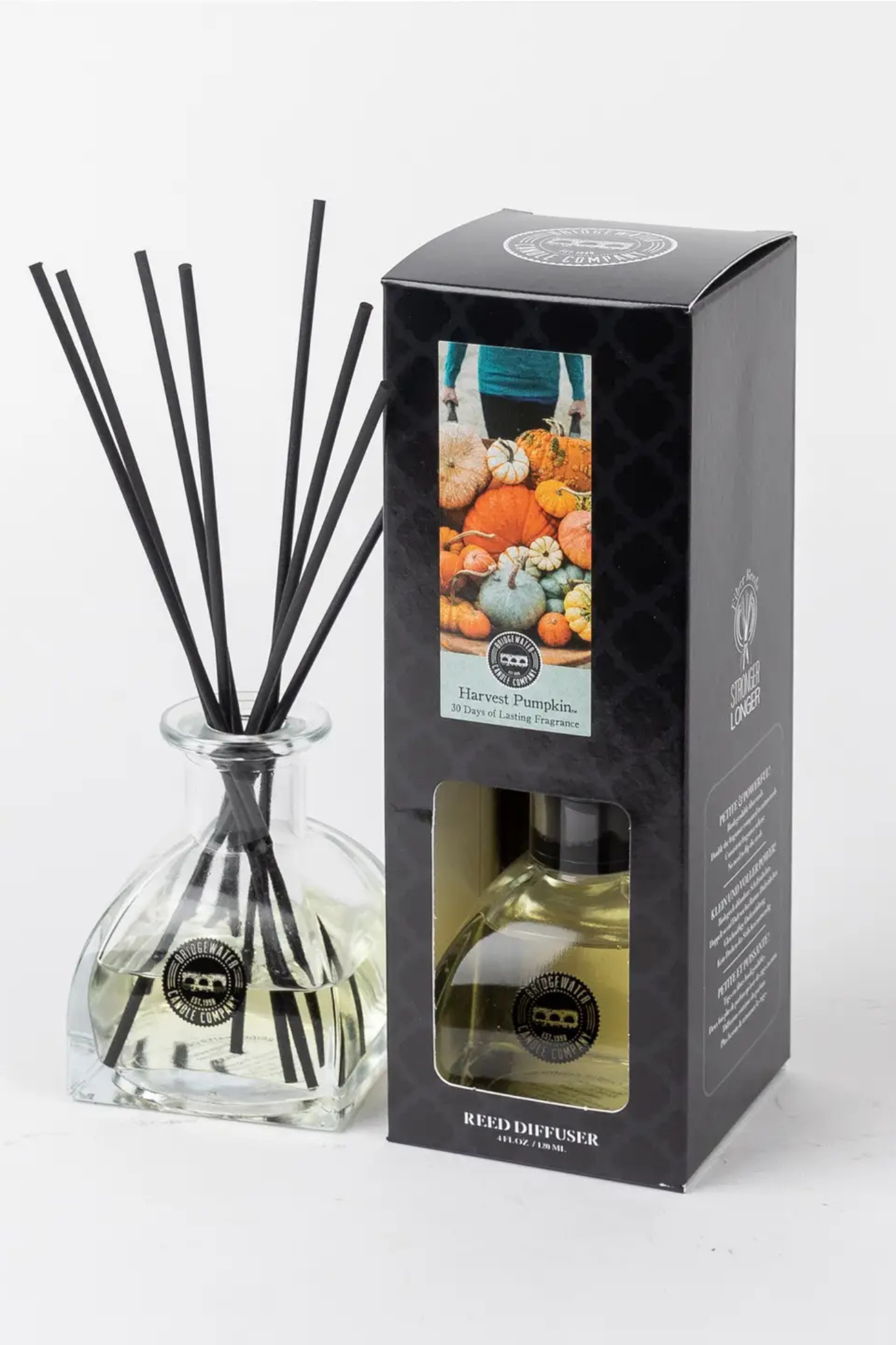 A reed diffuser set with a clear glass bottle, black reeds, and a black retail box featuring a window and a fall pumpkin illustration. The brand name Red Distilled is visible on the box and bottle label.