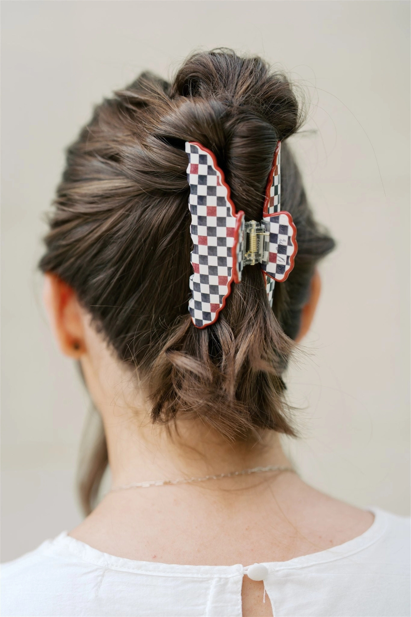 Person with a checkered hair clip in their hair against a plain background