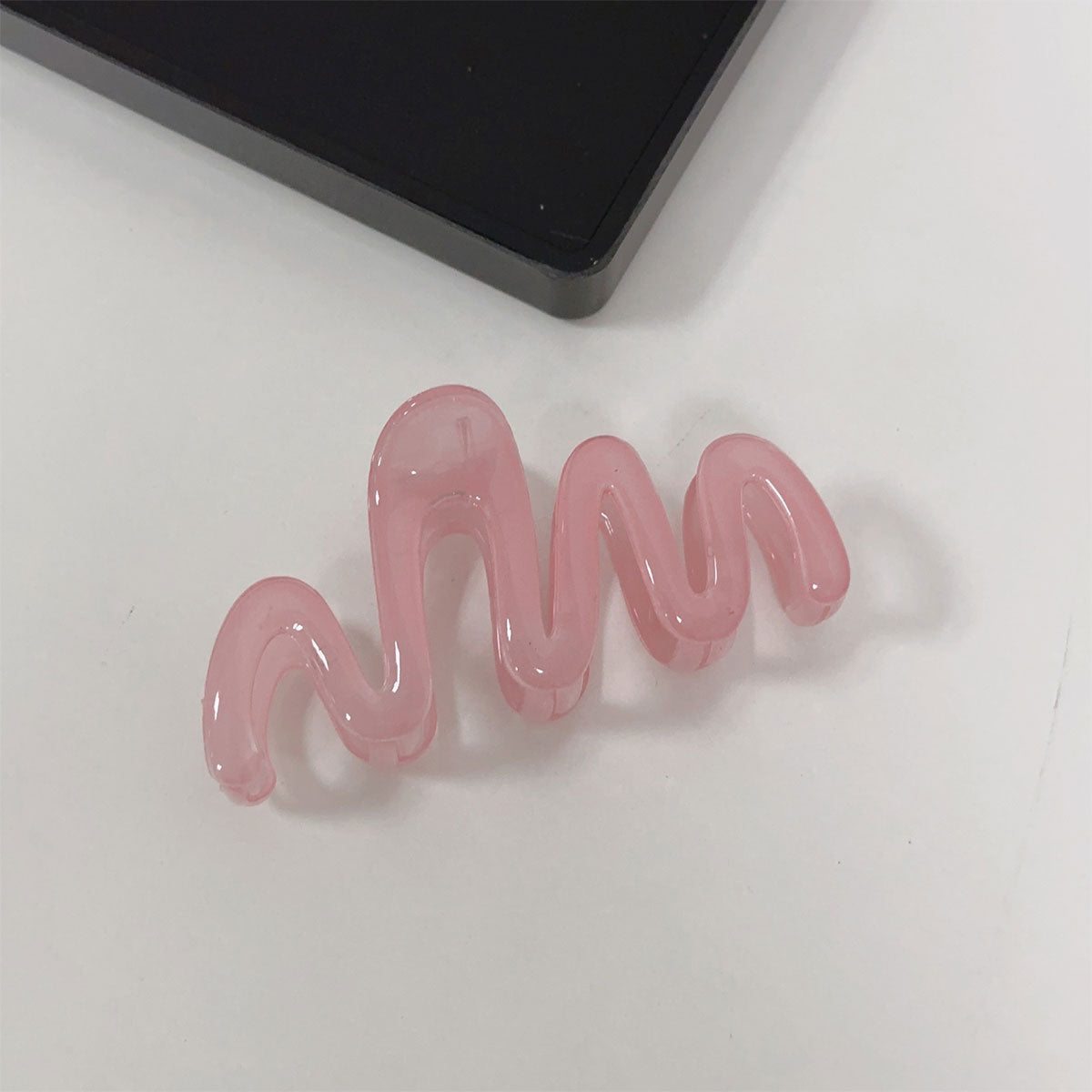 Pink hair clip with wavy design on a white background