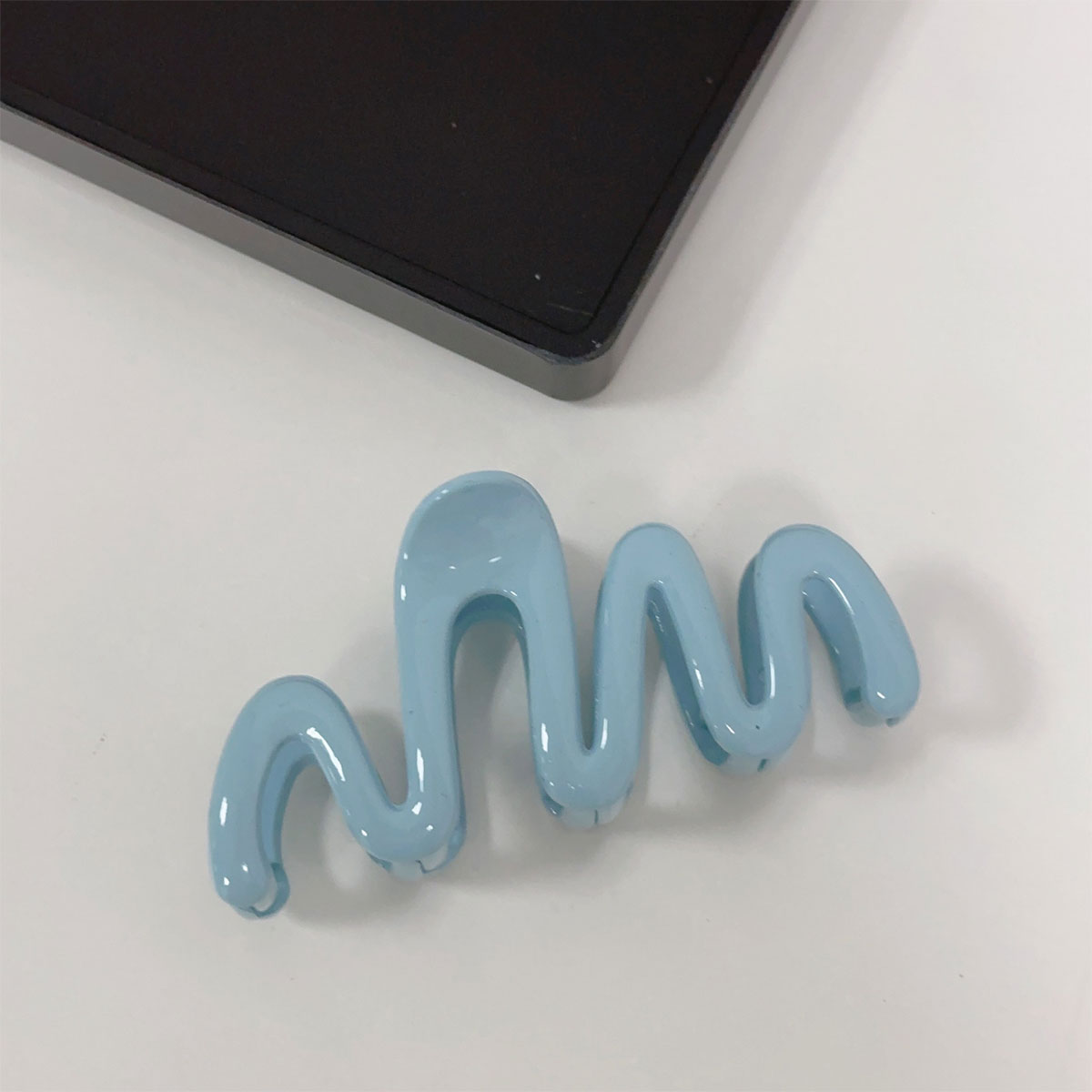 Blue hair clip shaped like a wavy line on a white background