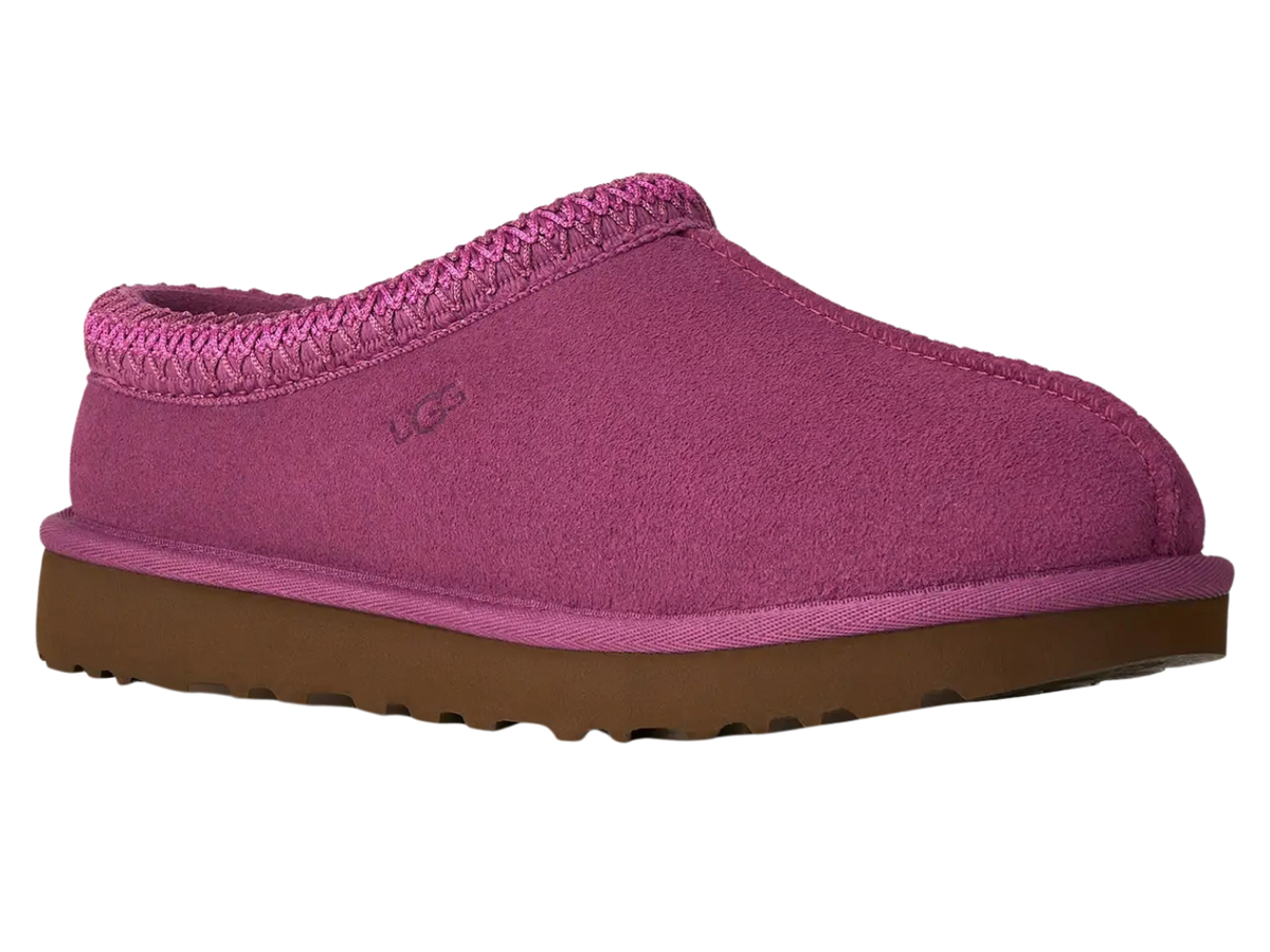 A single UGG slip-on clog shoe in a vibrant magenta pink color, featuring a textured fabric upper, a braided trim around the collar, and a brown rubber sole, shown against a plain white background.