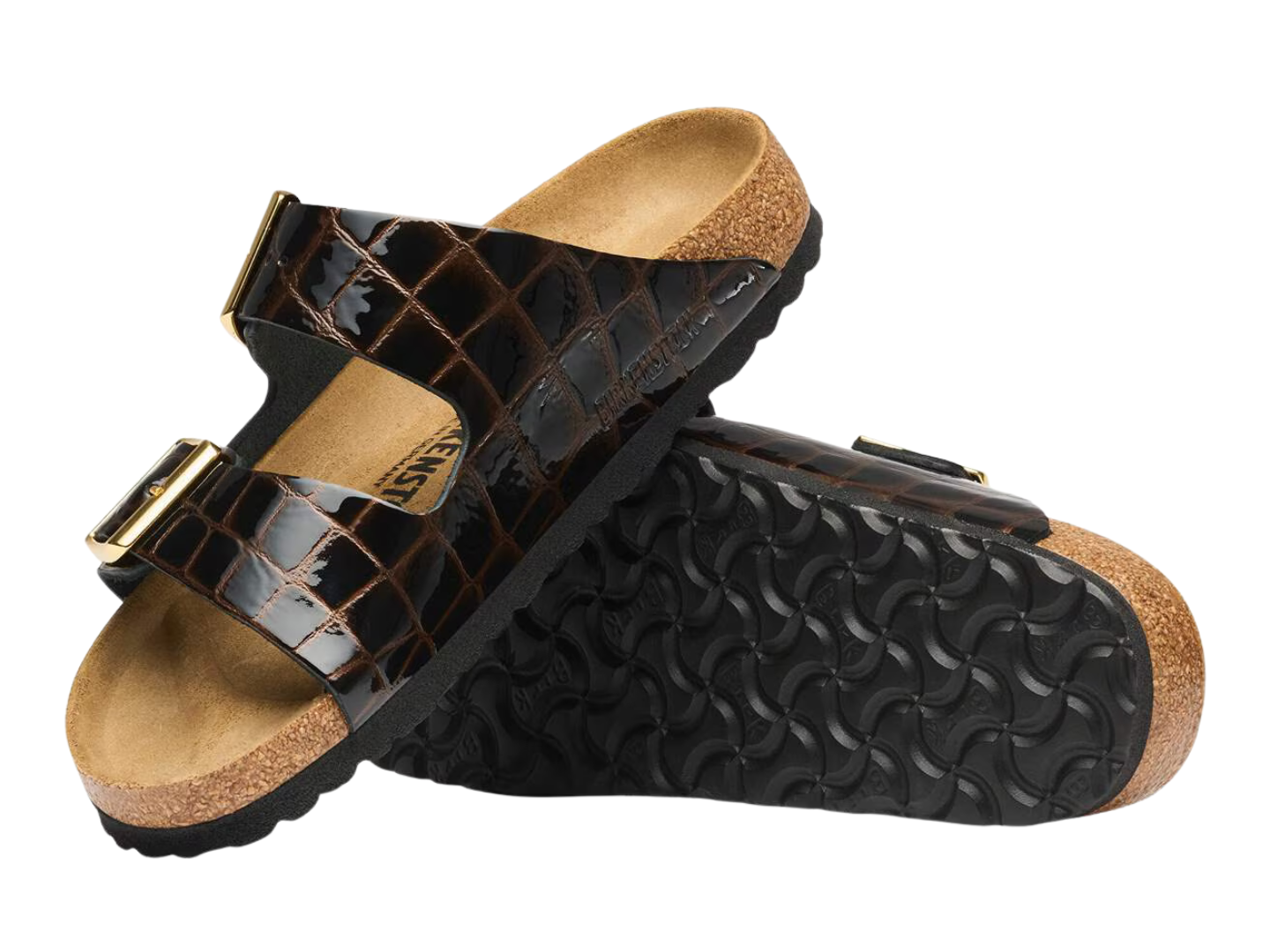 A pair of double-strap slide sandals with glossy black crocodile-embossed straps, gold-tone buckle details, and a natural cork footbed and sole edge, shown against a plain white background.