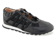 A black low-top sneaker with a mix of smooth leather and mesh panels, featuring a white midsole and a black treaded outsole, shown against a plain white background.