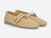 A pair of woven straw ballet flats with metallic gold double straps and gold-tone buckle details, shown on a light gray background.