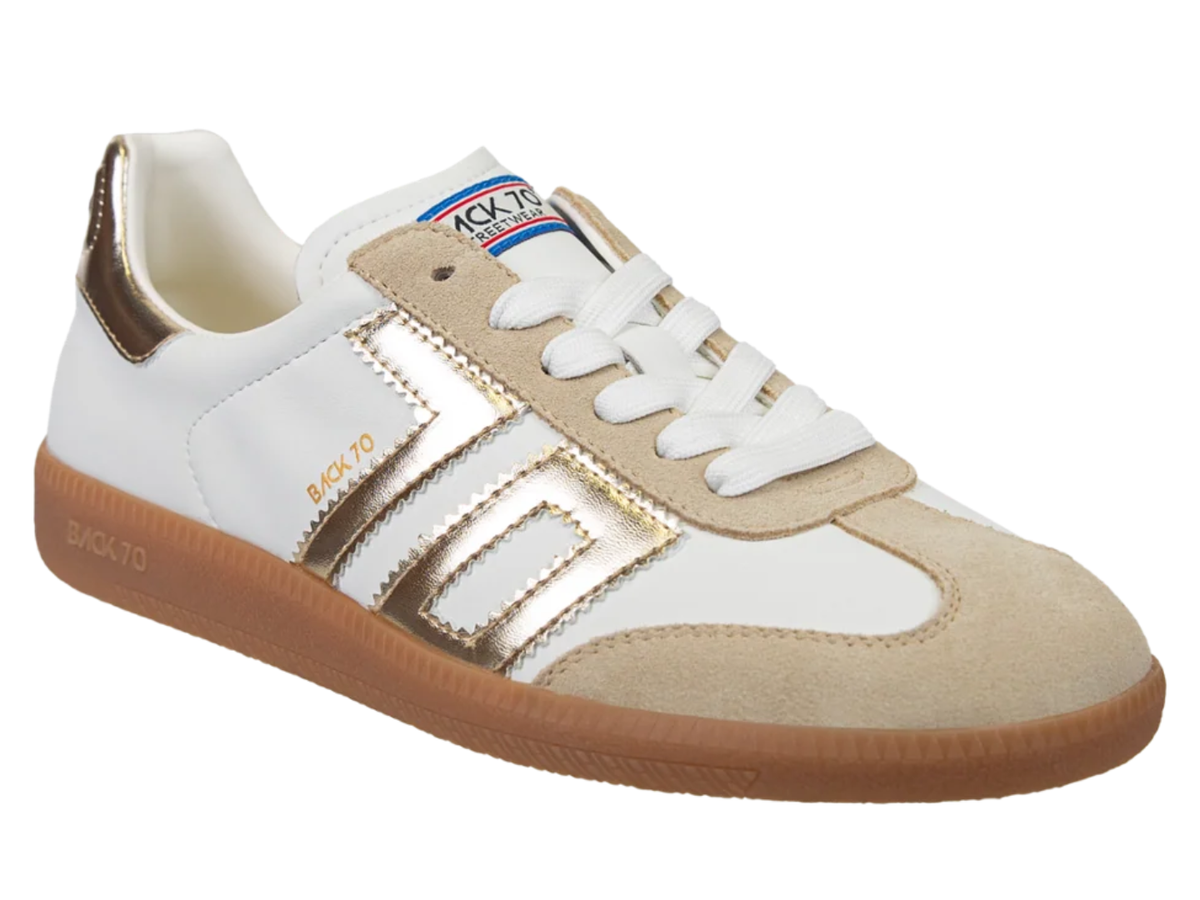 A low-top Bucko sneaker featuring a white leather upper with beige suede overlays, metallic gold side stripes, a white laces, and a brown gum sole.