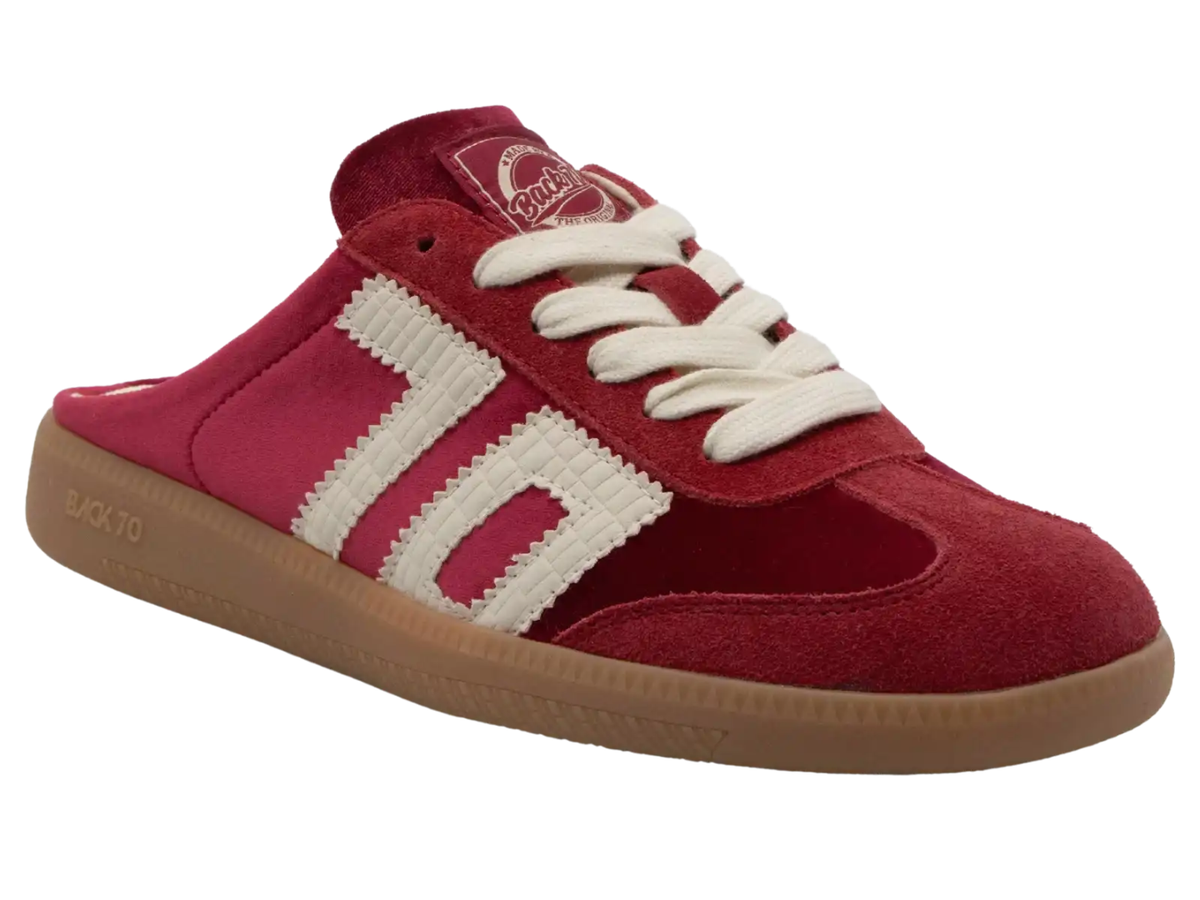 A red suede and fabric low-top slip-on sneaker with white textured side stripes, white laces, and a brown gum sole, shown on a plain white background.