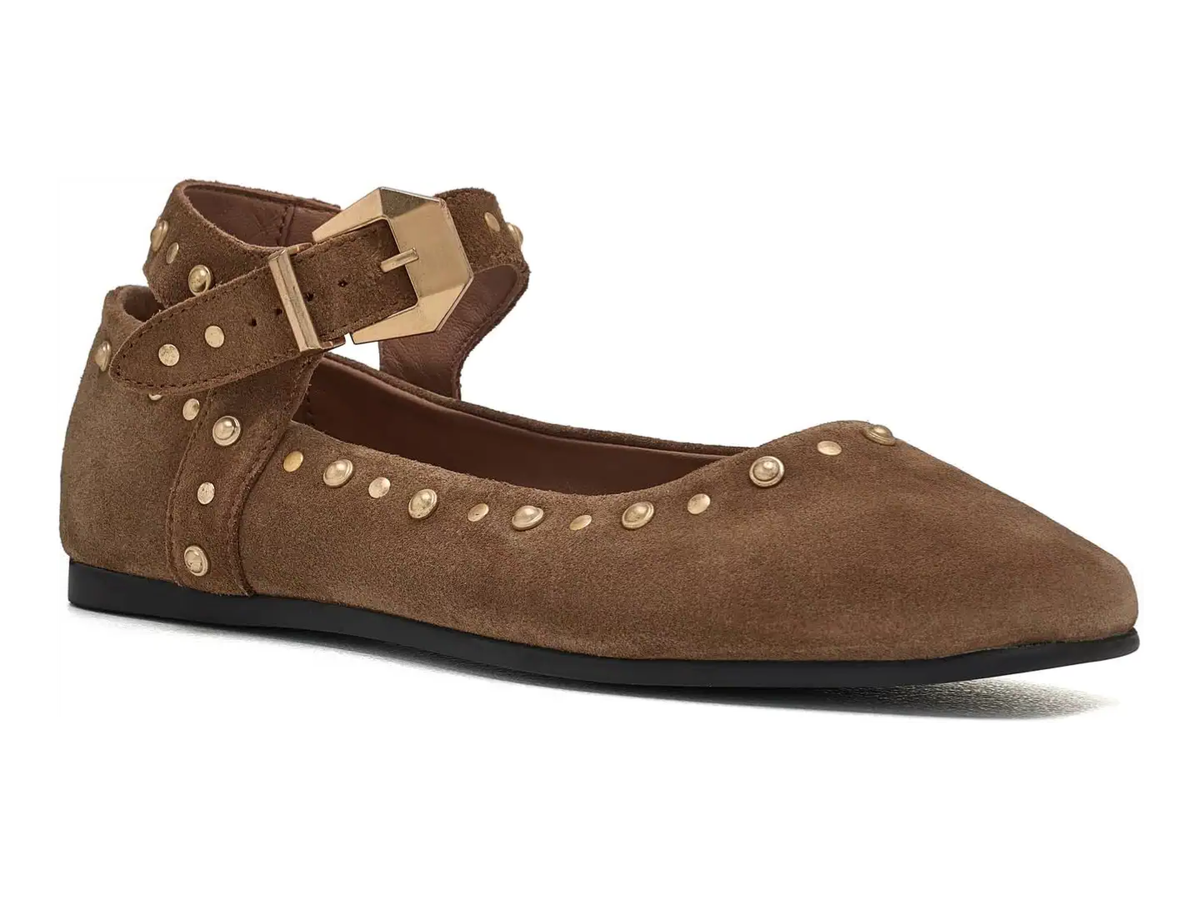 A brown suede flat shoe with an ankle strap, gold-tone studs, and a gold buckle, shown from a side profile on a white background.