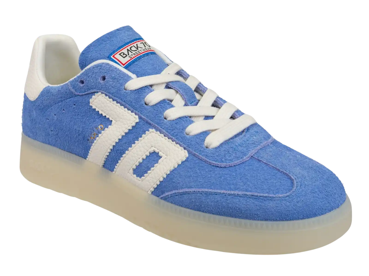 A blue suede sneaker with white accents, featuring a large white '70' logo on the side, white laces, and a translucent cream-colored sole, shown against a plain white background.