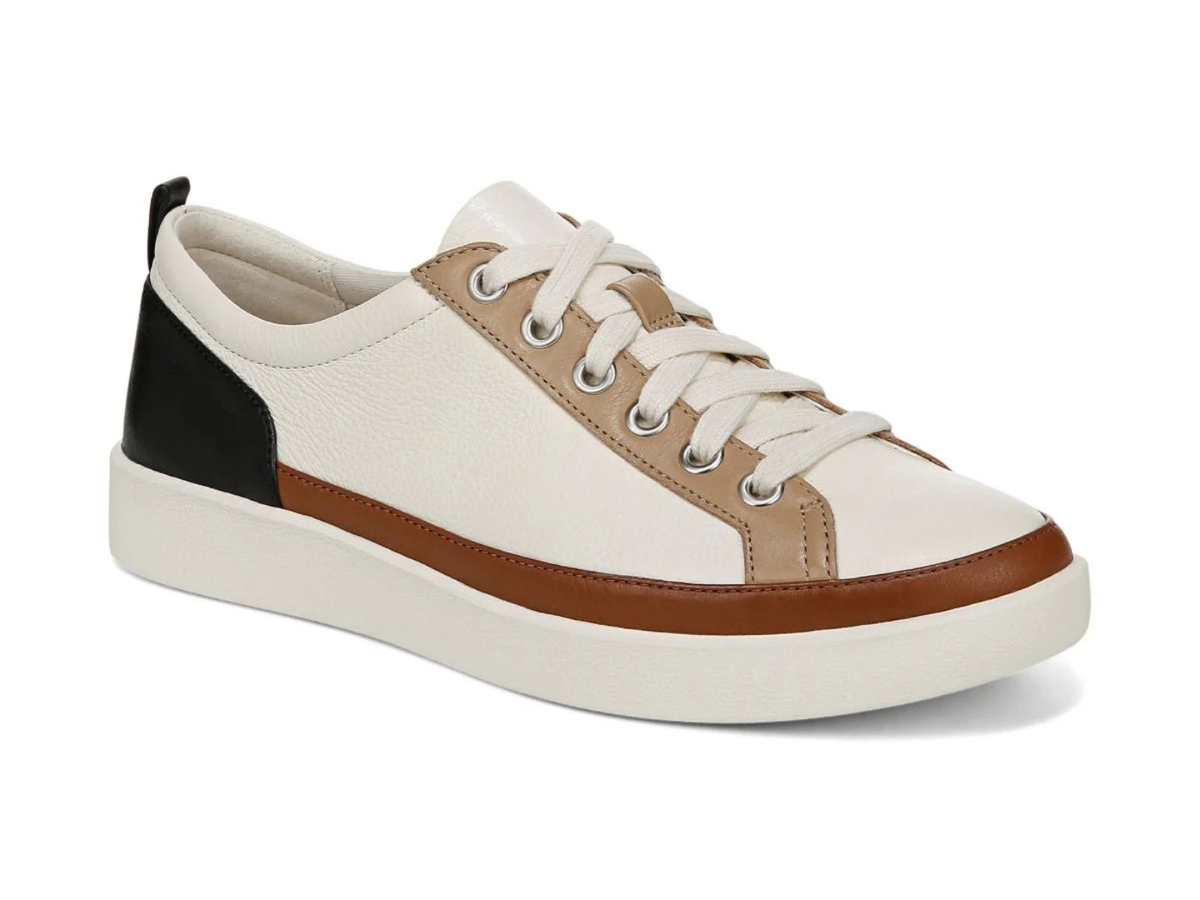 A low-top sneaker with a cream-colored leather upper, tan leather accents, a black heel tab, and a brown rubber toe bumper and midsole stripe, set against a plain white background.