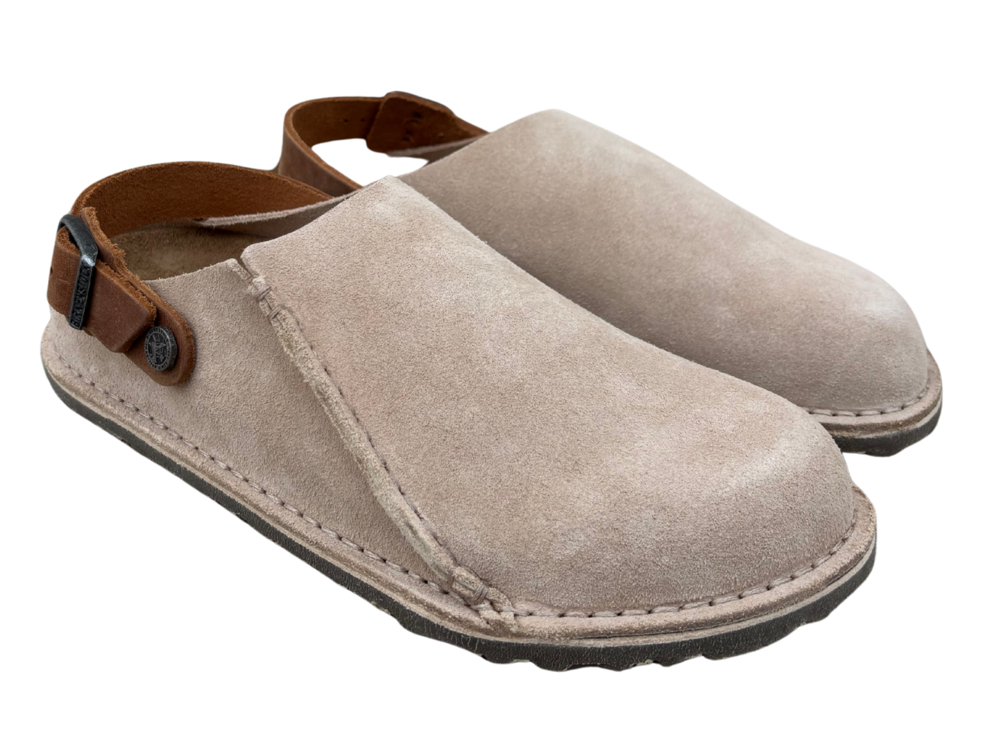 A pair of light taupe suede slip-on clogs with brown leather ankle straps and a dark sole, shown on a plain white background.