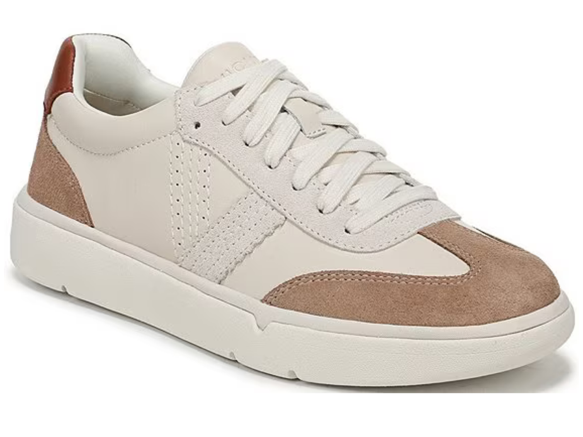 A low-top sneaker featuring cream-colored leather panels, tan suede overlays, white laces, and a chunky white sole, shown from a three-quarters angle on a white background.