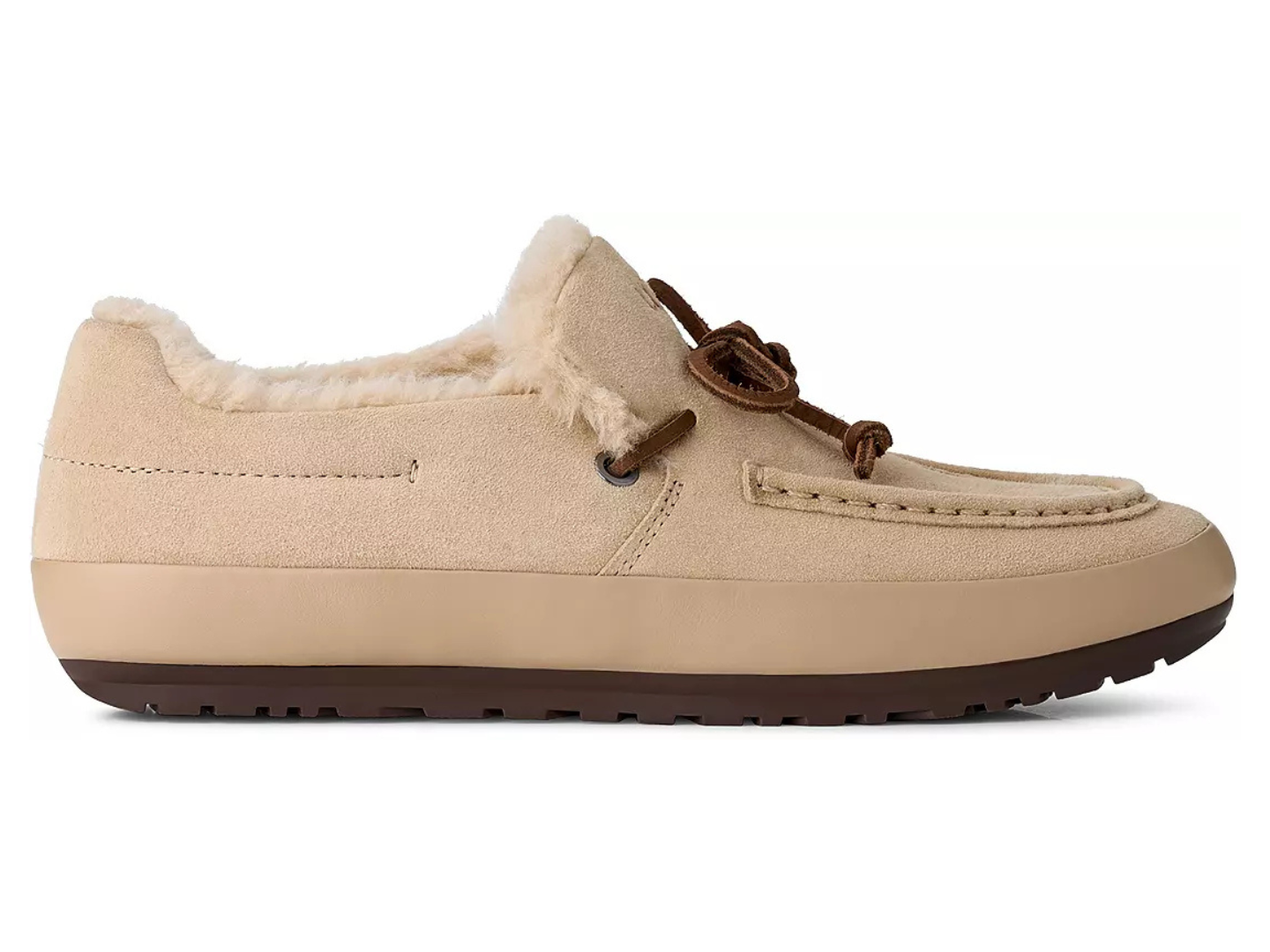 A beige suede slip-on moccasin-style shoe with a plush cream shearling lining and dark brown laces, shown in a side profile on a white background.