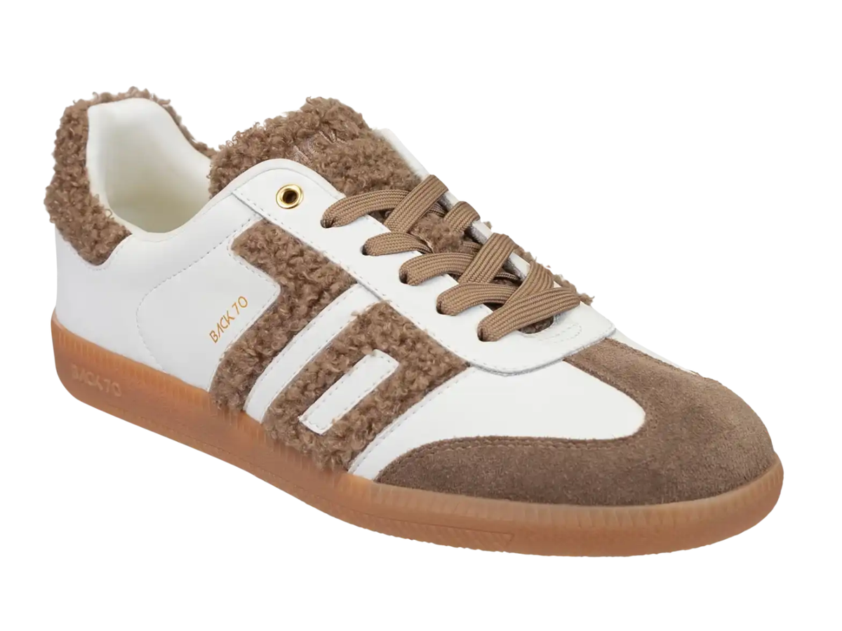 A low-top sneaker with a white leather upper, brown suede overlays, fuzzy brown sherpa lining, matching brown laces, and a gum brown sole. The side displays the brand name 'BACK TO' in gold lettering.