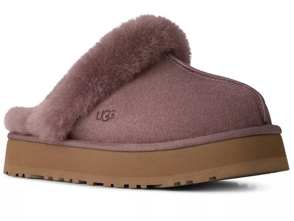 A single UGG slip-on mule slipper in a dusty mauve suede with a matching faux-fur collar and a thick tan platform sole, shown from a side profile on a white background.
