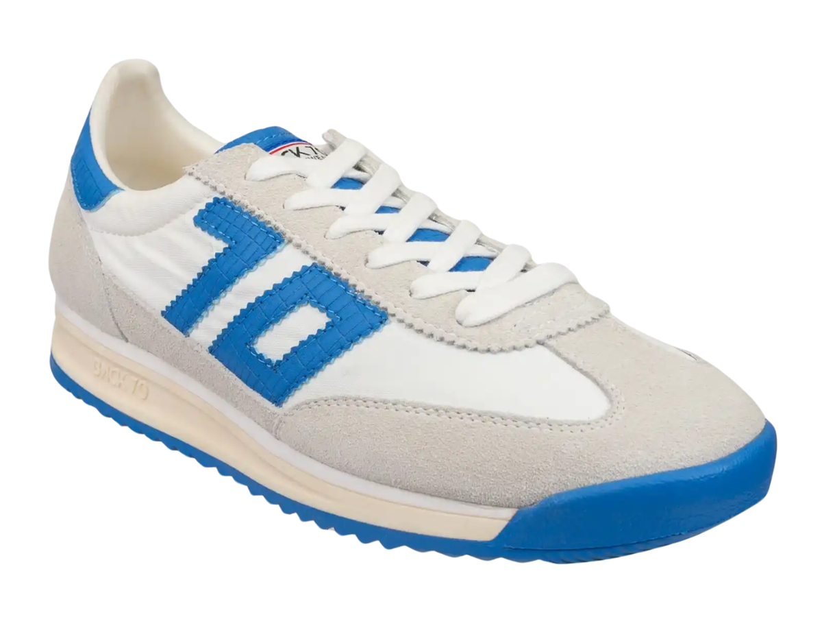 A low-top sneaker in white and light beige suede with bright blue accents, including a large '10' logo on the side, blue heel tab, and blue outsole.
