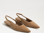 A pair of pointed-toe slingback flats in tan suede, shown on a clean white background. The shoes feature a low block heel and a small gold buckle at the back of the slingback strap.